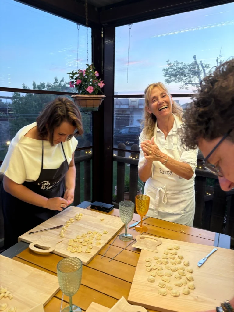 Enza smiling near guests making fresh pasta together